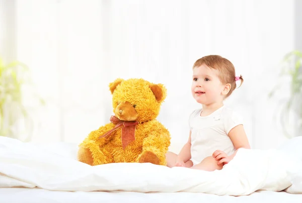 Linda niña abrazando oso de peluche en la cama — Foto de Stock