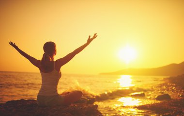 Kumsalda yoga gün batımında. Yoga yaparken kadın
