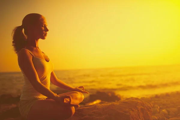 Mujer meditando en pose de loto en la playa al atardecer — Foto de Stock