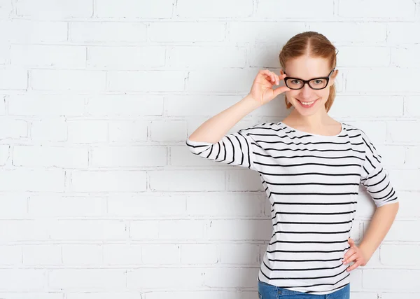 Menina feliz estudante em óculos em uma parede de tijolo branco em branco — Fotografia de Stock