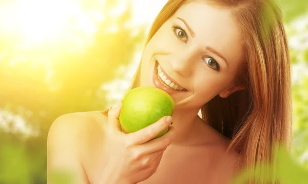 Beautiful young woman eating green apple in the summer on the na — Stock Photo, Image