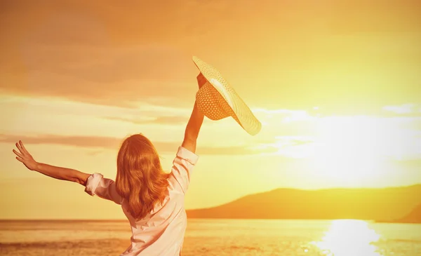 Happy woman in hat is back  opened his hands, enjoys sunset — Stock Photo, Image