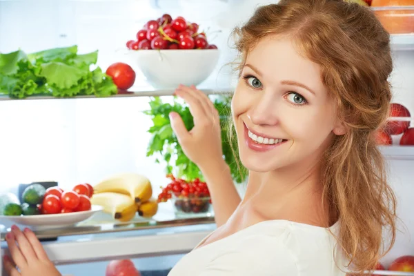 Mulher feliz e geladeira aberta com frutas, legumes e ele — Fotografia de Stock