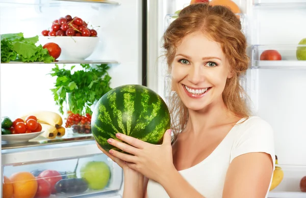 Счастливая женщина и открытый холодильник с фруктами, овощами и он — стоковое фото