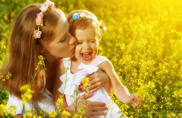 Happy family in summer meadow, mother kissing little daughter ch — 图库照片