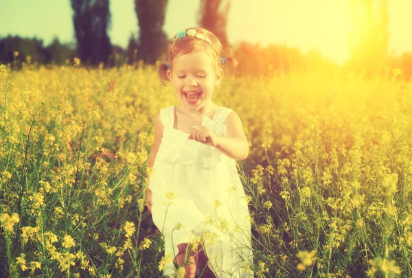 Happy little child girl running on field with yellow flowers — Stock Photo, Image
