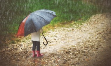 happy baby girl with  umbrella in the rain runs through