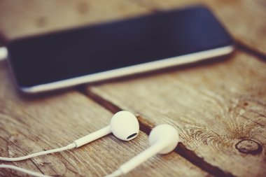 cep telefonu ve kulaklık eski bir ahşap masa üzerinde yatıyordu