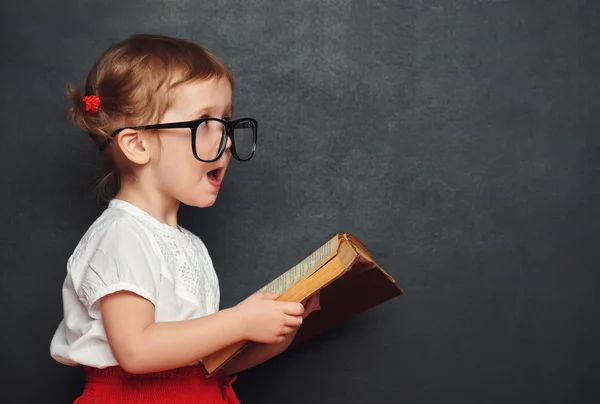 Engraçado menina feliz estudante com livro de quadro negro — Fotografia de Stock