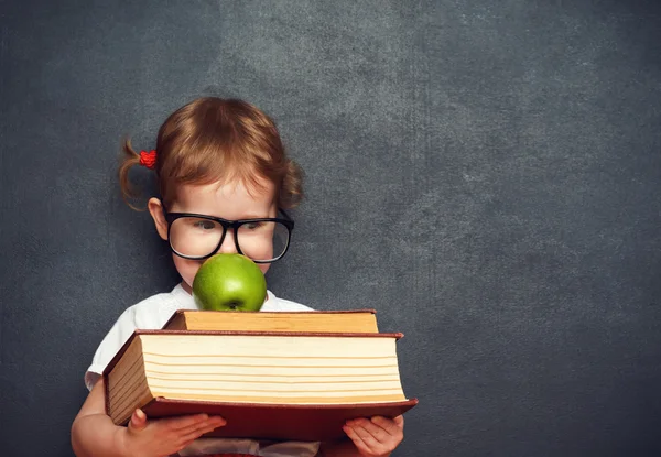 Flicka skolflicka med böcker och äpple i en skolans styrelse — Stockfoto