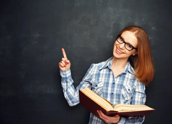 Glückliche Studentin mit Brille und Buch von leerer Tafel — Stockfoto