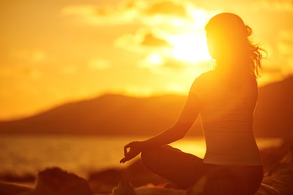 Mulher meditando em lótus posar na praia ao pôr do sol — Fotografia de Stock