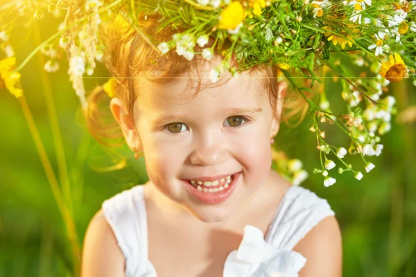 Divertido bebé feliz niña en una corona de flores en la naturaleza riendo en su —  Fotos de Stock