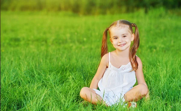 Menina criança feliz em vestido branco deitado na grama Verão — Fotografia de Stock