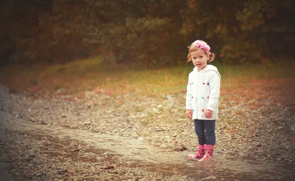 Tristezza carina bambina sotto la pioggia che gioca sulla natura — Foto Stock