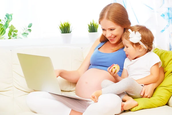 Famille heureuse femme enceinte et enfant avec un ordinateur portable à la maison — Photo