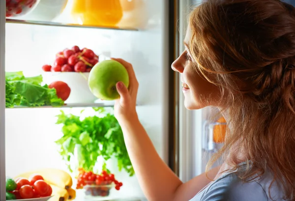 Нічний голод. Жінка в темряві на відкритому холодильнику — стокове фото