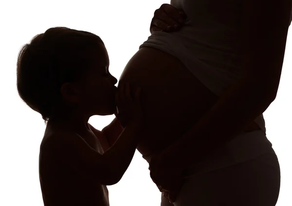 Gelukkige familie. Silhouet van kind zoenen buik van zwangere ma — Stockfoto