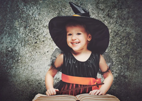 Halloween. Veselá malá čarodějnice s kouzelnou hůlkou a kniha conjur — Stock fotografie