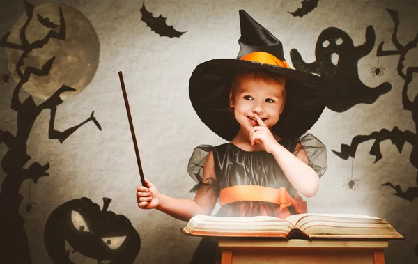 Halloween. cheerful little witch with magic wand and book conjur Royalty Free Stock Photos