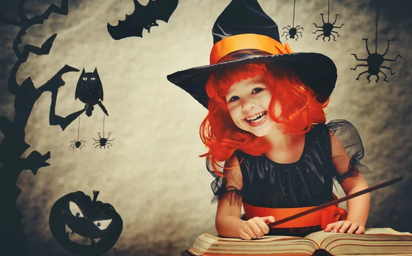 Halloween. cheerful little witch with magic wand and book conjur Stock Image