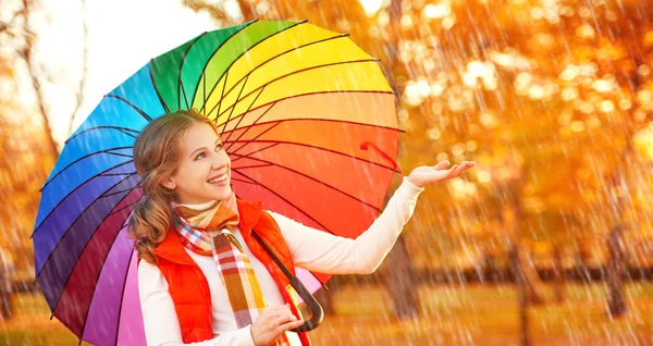 Mulher feliz com arco-íris guarda-chuva multicolorido sob a chuva em par — Fotografia de Stock