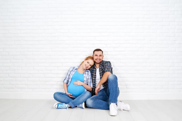 Feliz pareja marido y esposa embarazada cerca de pared de ladrillo en blanco — Foto de Stock