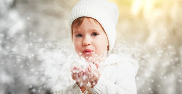 Menina feliz soprando flocos de neve no inverno ao ar livre — Fotografia de Stock