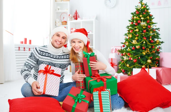 Lyckliga familjen paret med en present på julen hemma — Stockfoto