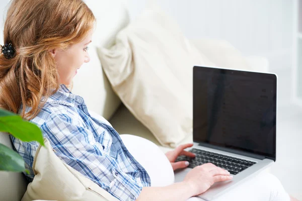 Gelukkig zwangere vrouw met een laptop thuis — Stockfoto