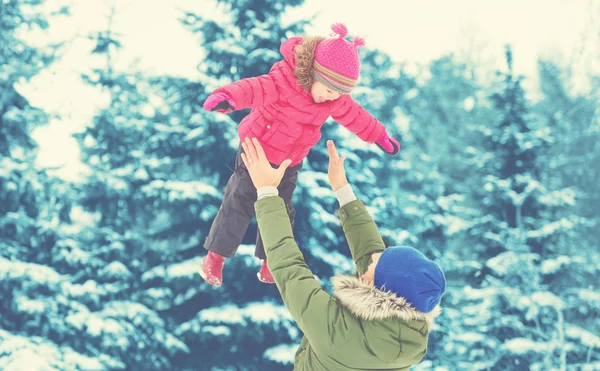 Happy family on winter walk. Dad throws up baby girl — Stock Photo, Image