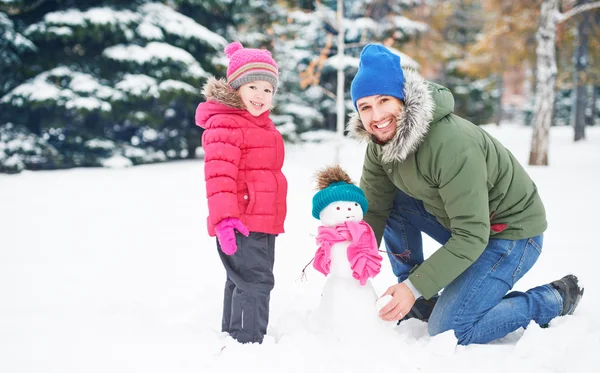 Šťastná rodina otce a dítě dívka dělá sněhulák v zimě — Stock fotografie