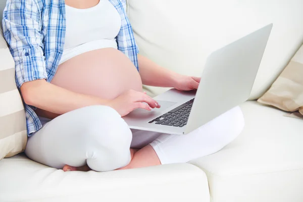 Беременная женщина с ноутбуком дома — стоковое фото