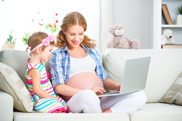 Happy family pregnant woman and child with a laptop at home