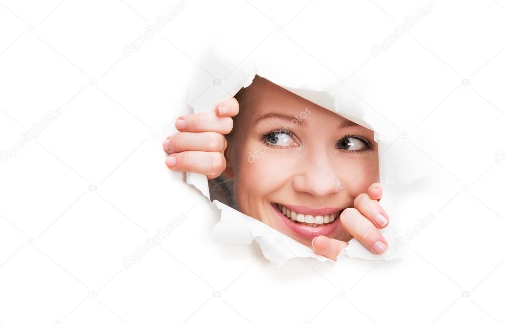 face of  woman peeking through a  hole torn in white paper poste