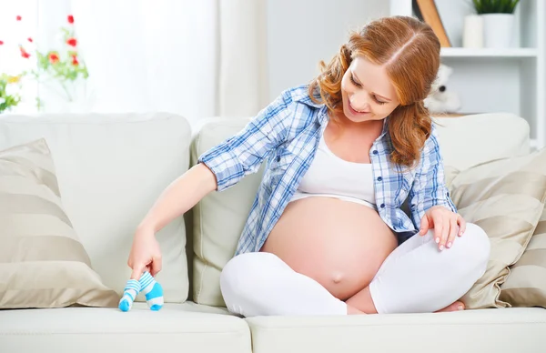 Szczęśliwa kobieta w ciąży jest odpoczynek w domu na kanapie i trzymając bl — Zdjęcie stockowe