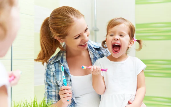 Feliz familia madre e hijo niña limpia los dientes con cepillo de dientes —  Fotos de Stock