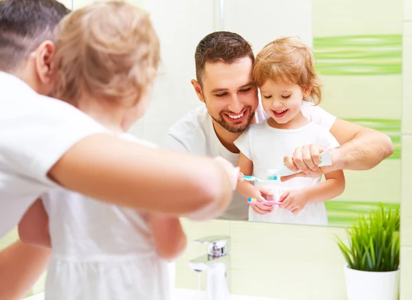 Feliz familia padre y niña cepillarse los dientes en albornoz — Foto de Stock