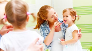 mutlu aile anne ve çocuk kız diş diş fırçası ile temizler 