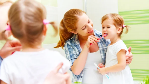 Família feliz mãe e criança menina limpa os dentes com escova de dentes — Fotografia de Stock