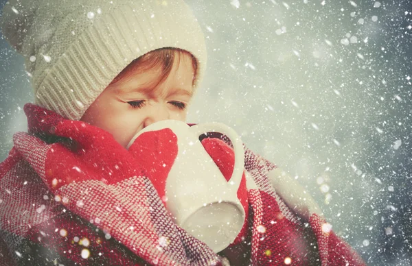 Fröhliches Kindermädchen mit einer Tasse Heißgetränk im kalten Winter im Freien — Stockfoto