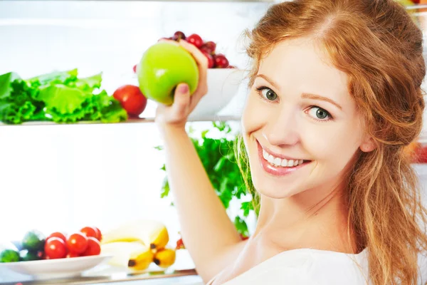 Mulher feliz com maçã e geladeira aberta com frutas, vegeta — Fotografia de Stock