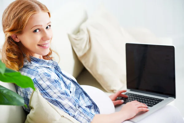 Mulher grávida feliz com um laptop em casa — Fotografia de Stock