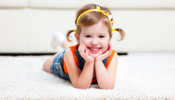 Menina feliz deitada no chão em casa — Fotografia de Stock