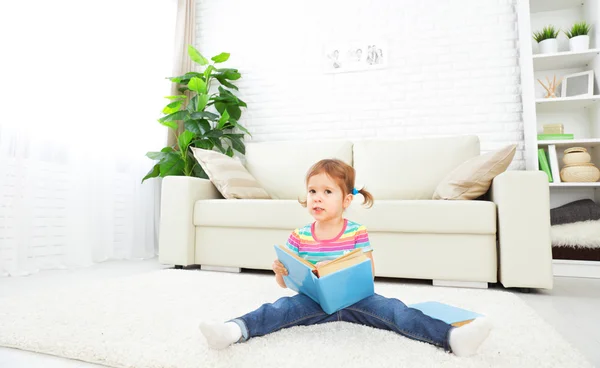 Aranyos kislány könyvével otthon ül a padló — Stock Fotó