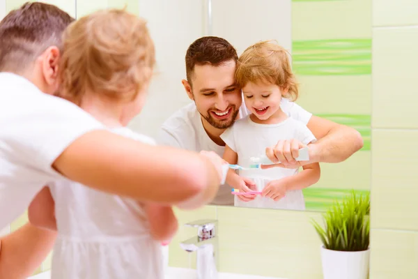 Feliz familia padre y niña cepillarse los dientes en albornoz —  Fotos de Stock