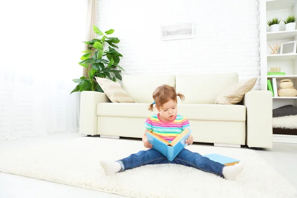 Schattige babymeisje het lezen van boek thuis zittend op de vloer — Stockfoto