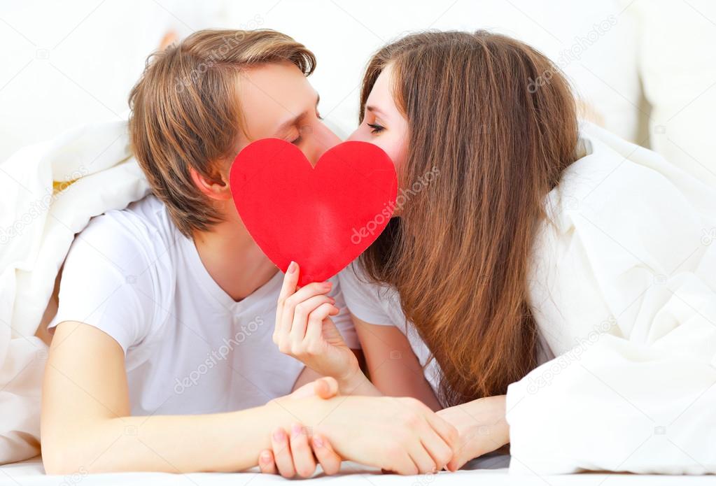 lover couple kissing with a red heart in bed