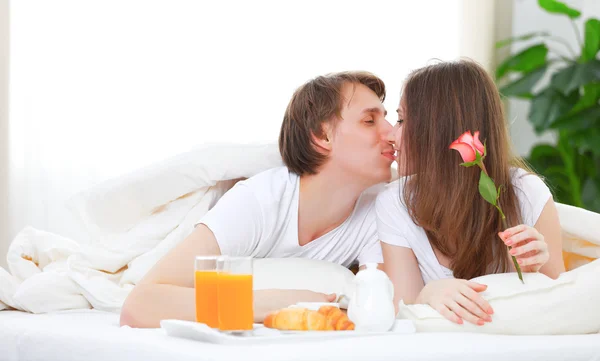 Casal amoroso beijando e tomando café da manhã na cama — Fotografia de Stock