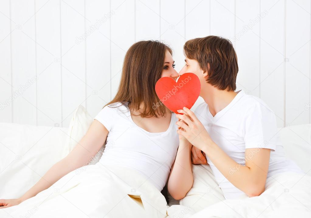 lover couple kissing with a red heart in bed